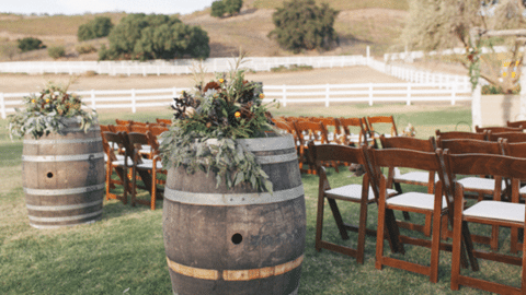 Outdoor wedding with barrel kegs at beginning of aisle